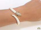 Top open serpentine bracelet in white enamel with  gold plated details and cubic zirconia stones head