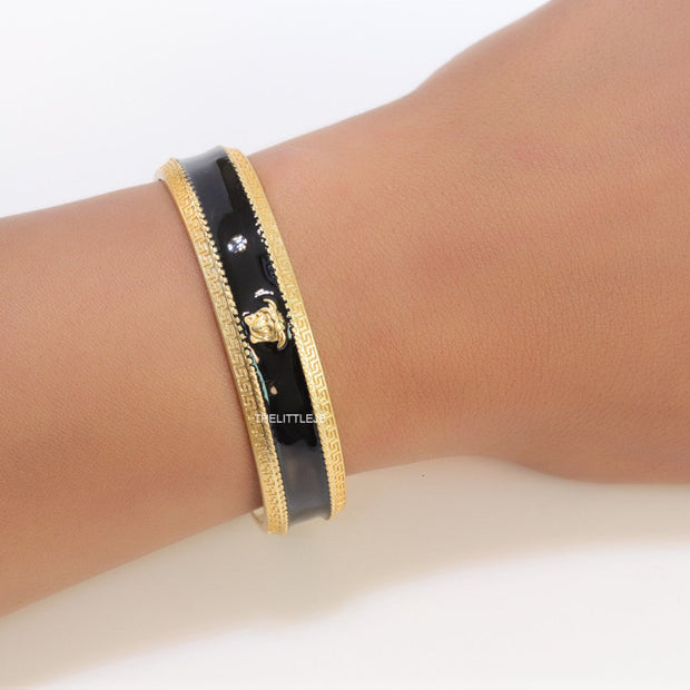 Band style black enamel bracelet with gold plated details and gold plated Medusa face motif