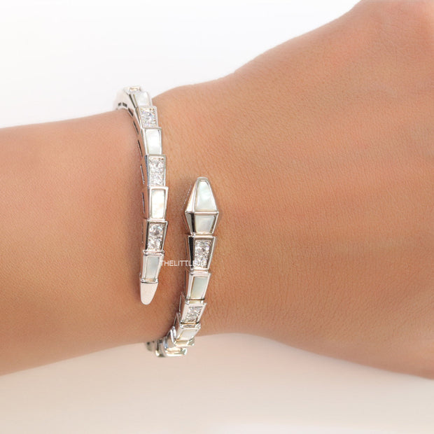 Open top platinum plated minimal serpentine bracelet with cubic zirconia stones and pearl white stones.
