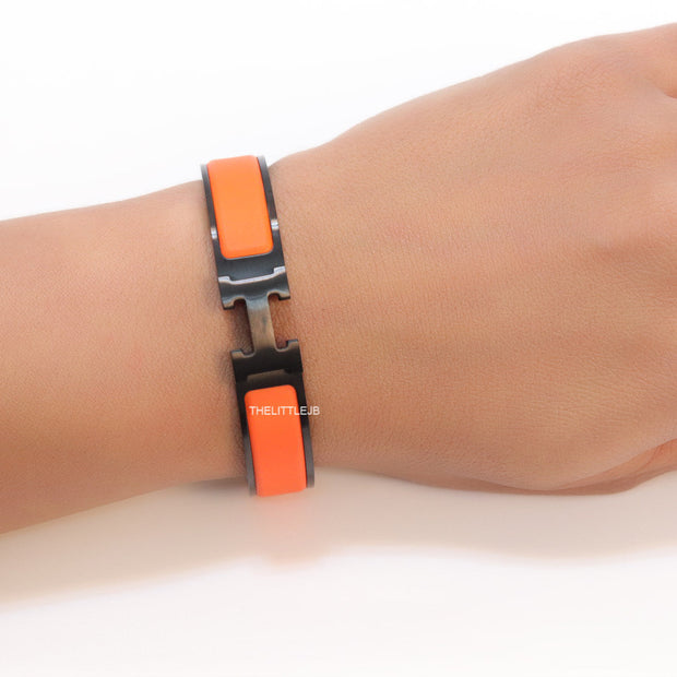 Premium collection band style bracelet in matt orange with black metallic details and black T alphabet motif