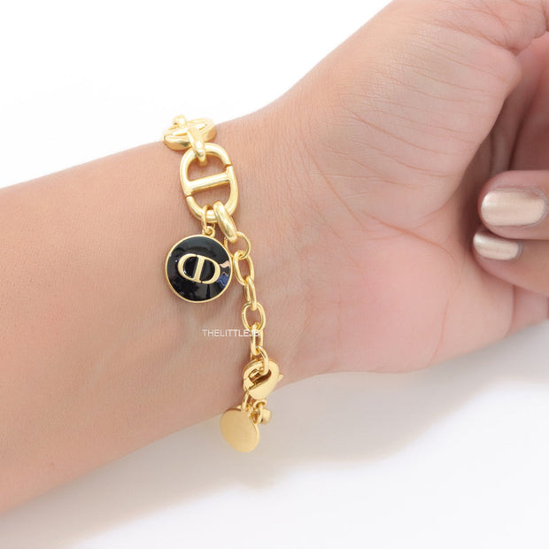 Gold plated link chain bracelet with charms, trinkets and black enamel charm with alphabets