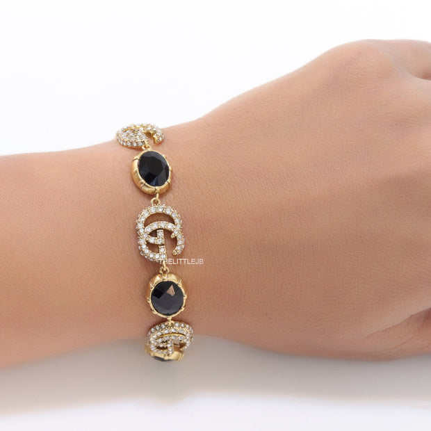 Gold plated linked chain bracelet with black stones and twin G alphabet motif