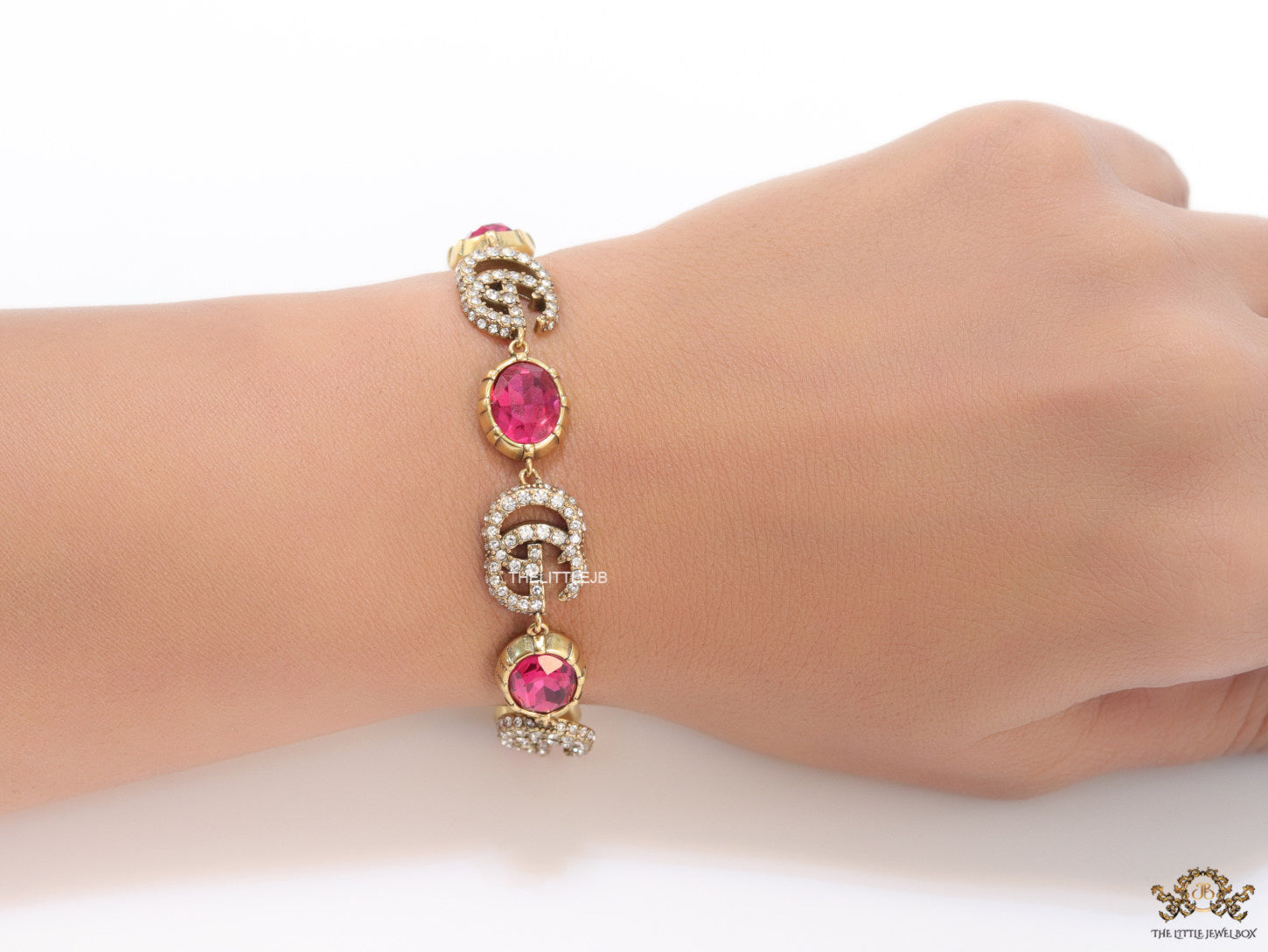 Gold plated linked chain bracelet with gold plated cubic zirconia stones twin G alphabet motifs and gold plated pink cubic zirconia stones