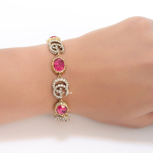 Gold plated linked chain bracelet with gold plated cubic zirconia stones twin G alphabet motifs and gold plated pink cubic zirconia stones