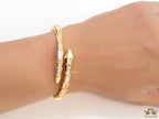 Open top gold plated minimal serpentine bracelet with cubic zirconia stones and pearl white stones.