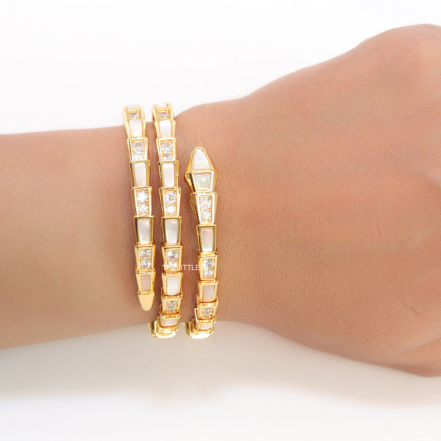 Triple line gold plated minimal serpentine bracelet with cubic zirconia stones and pearl white stones.