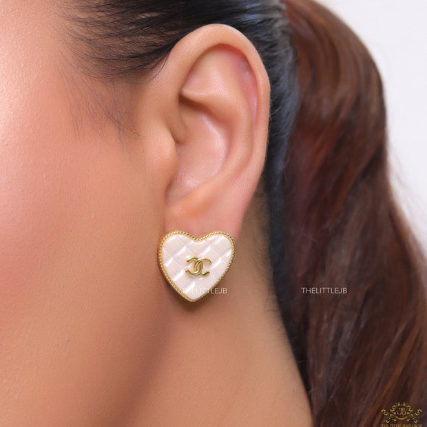 White textured heart shaped studs with twin C motif in golden finish