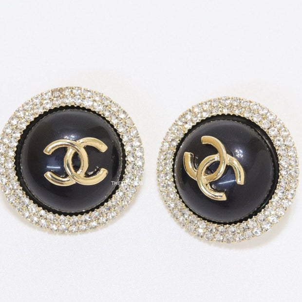 Round black stud earrings with golden twin C motifs lined with cz