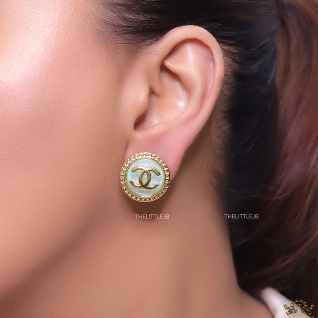 Twin C motif gold plated round studs on mint green acrylic base