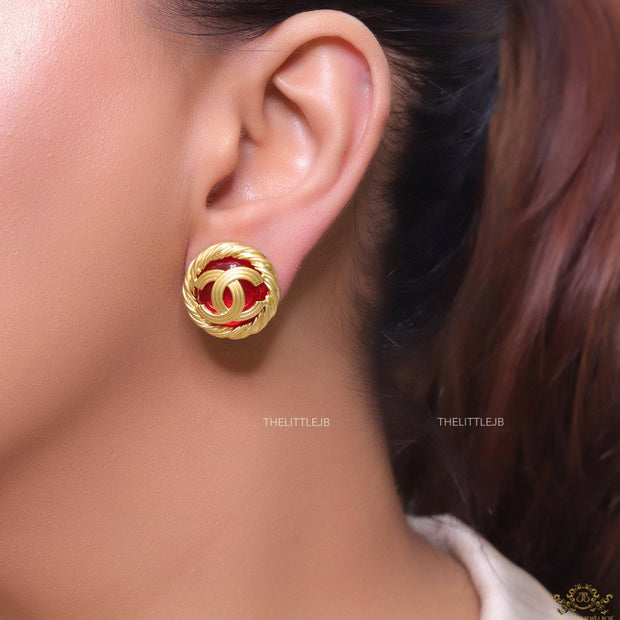 Twin C motif matt gold plated round studs on red base