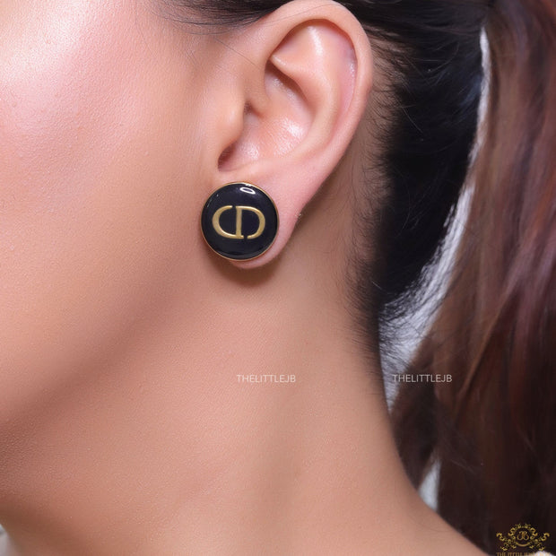 Round black stud earrings with golden alphabets