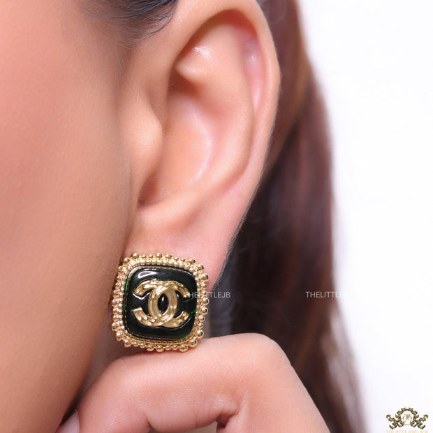 Square black and golden stud earrings with golden twin C motifs