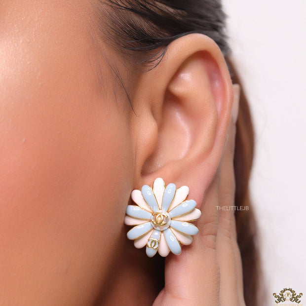 Off-white and soft blue daisy studs with golden details twin alphabet double C motif.